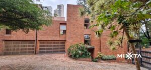 Fachada: Casa con arquitectura atípica en Medellín El Poblado con diseño por medios niveles y jardín en L Interior: Habitación con techo a dos aguas y tragaluces triangulares Medellín